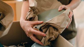 crop-woman-with-packing-paper-and-belongings