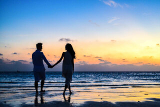 man-and-woman-holding-hands-walking-on-seashore