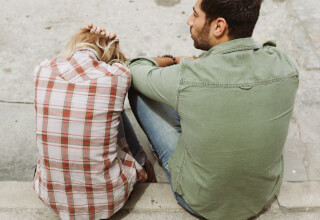 man-and-woman-sitting-on-sidewalk