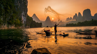 person-s-on-boat-throwing-fishing-net